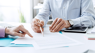 Desk top with NCR ATM service contract being reviewed by two sets of hands